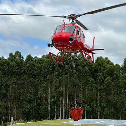 Helicóptero vermelho Henrimar em voo sobre a floresta